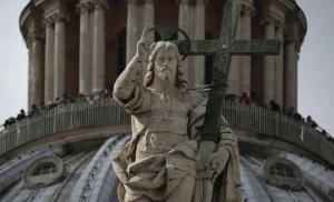 The statue of the Christ is seen in front of the dome of Saint Peter's Basilica at the Vatican